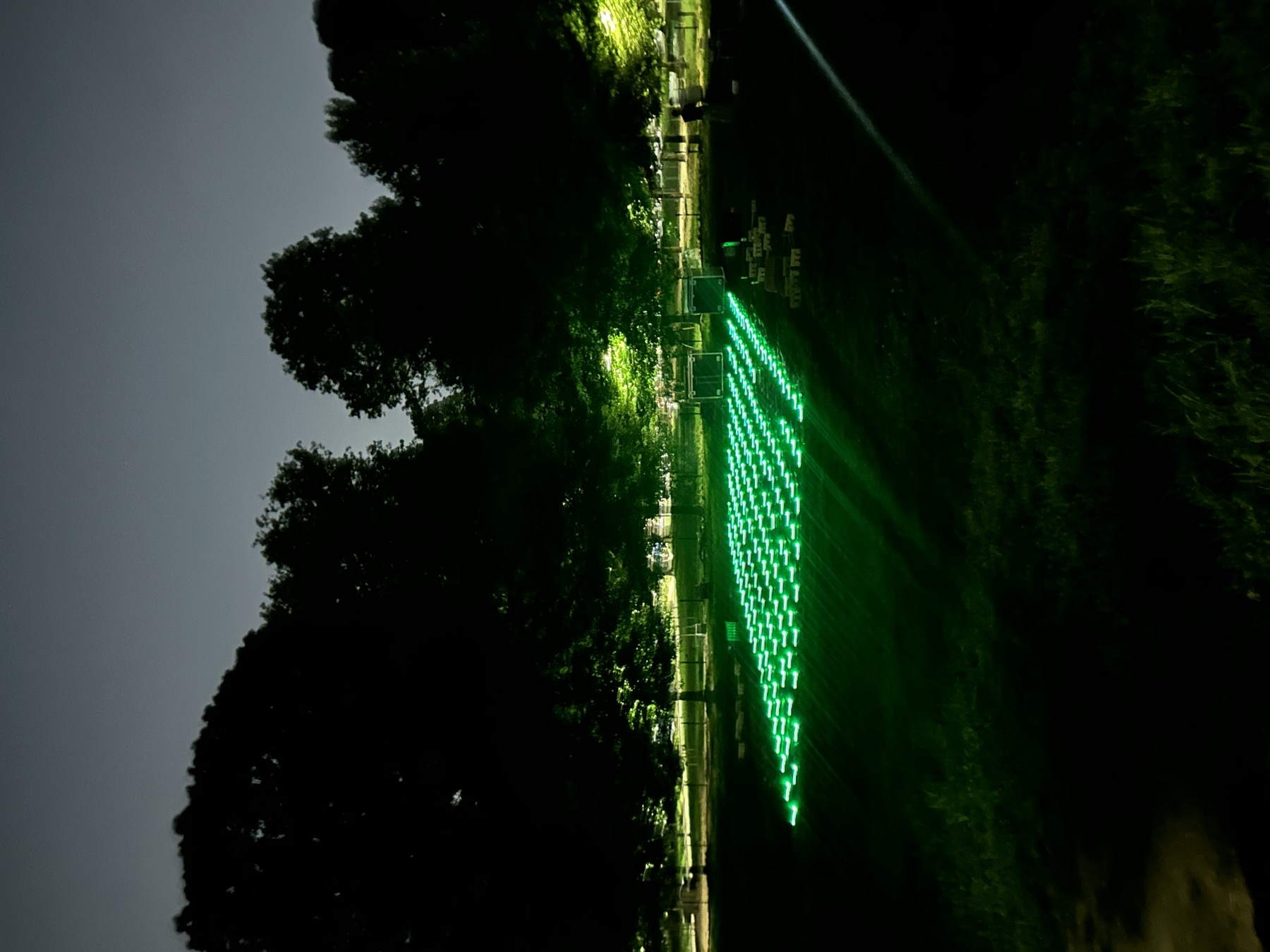 The drone grid glowing green on the grass at dusk